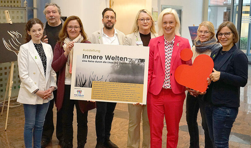 8 Personen halten ein Schild in den Händen mit der Aufschrift 'Innere Welten'